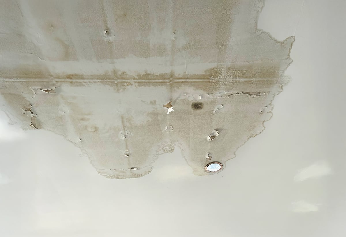 Brown water stain on a ceiling caused by a leaking roof