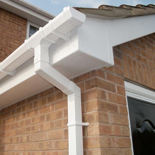 White PVC gutter and downspout installed on a brick house exterior